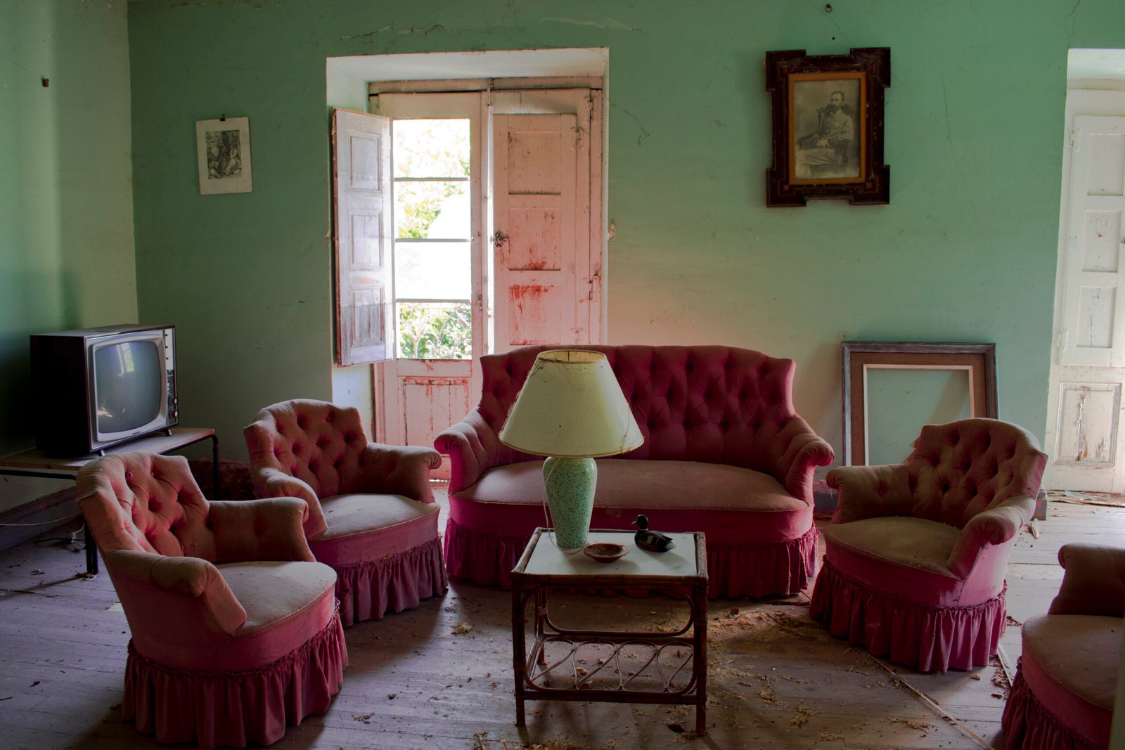 Sala de estar antigua con muebles rosados y televisor.