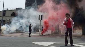 Personas con humo de colores en calle.
