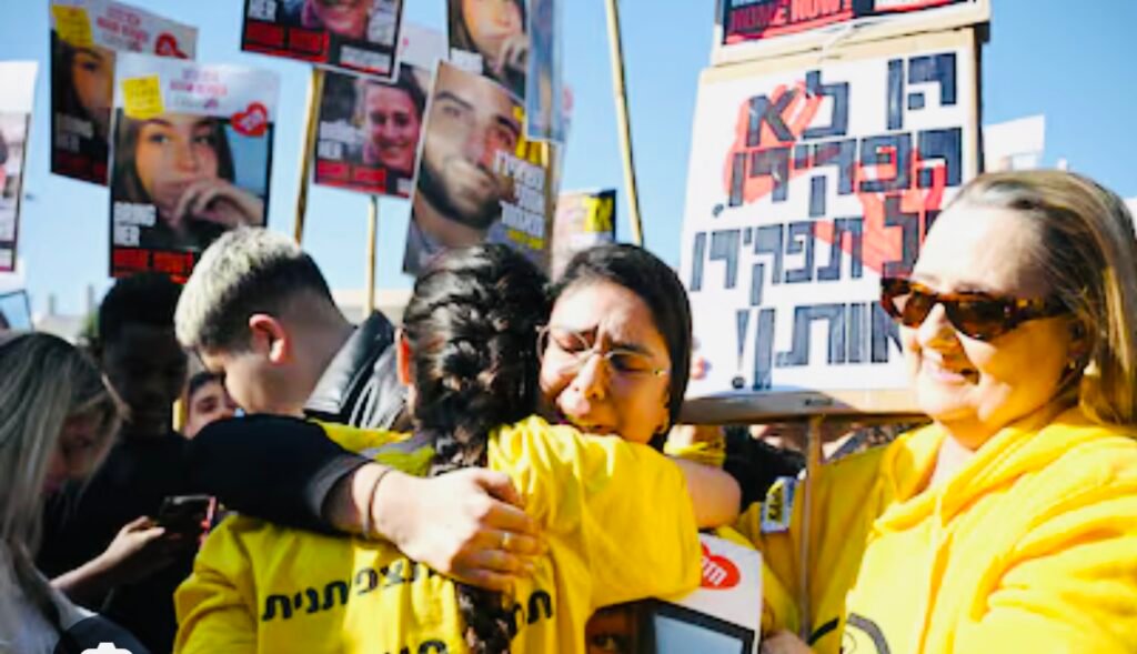 Personas abrazándose en manifestación con carteles alrededor.