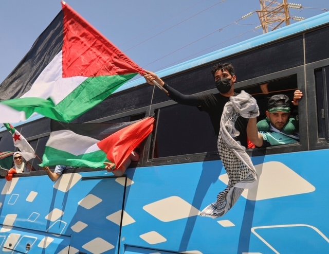 Personas en autobús con banderas palestinas.