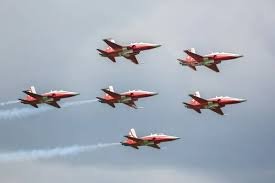 Formación aérea de seis aviones rojos sobrevolando.