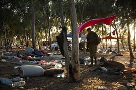 Campamento improvisado entre árboles con basura alrededor.